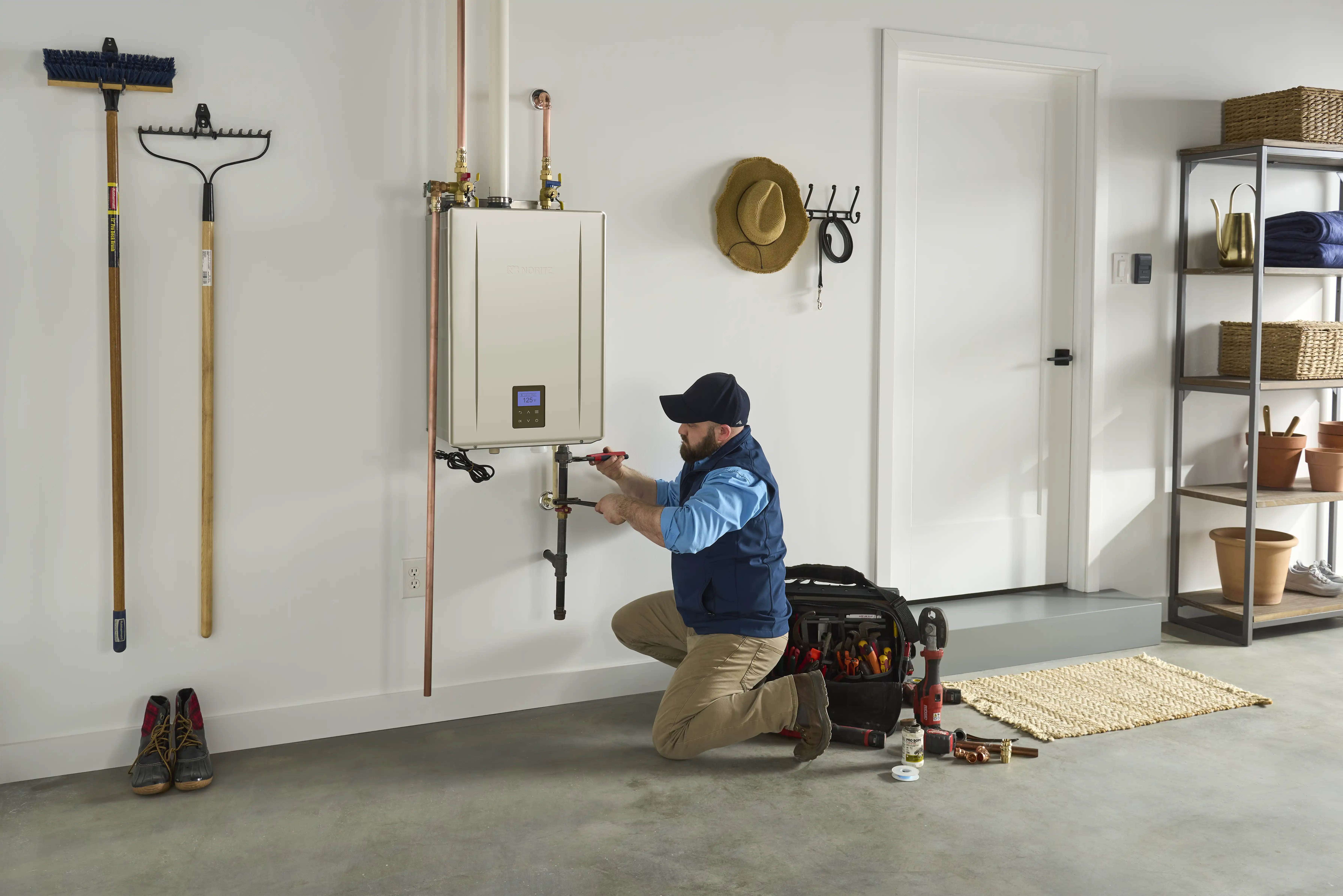 Technician servicing a wall-mounted Noritz tankless water heater in a clean garage