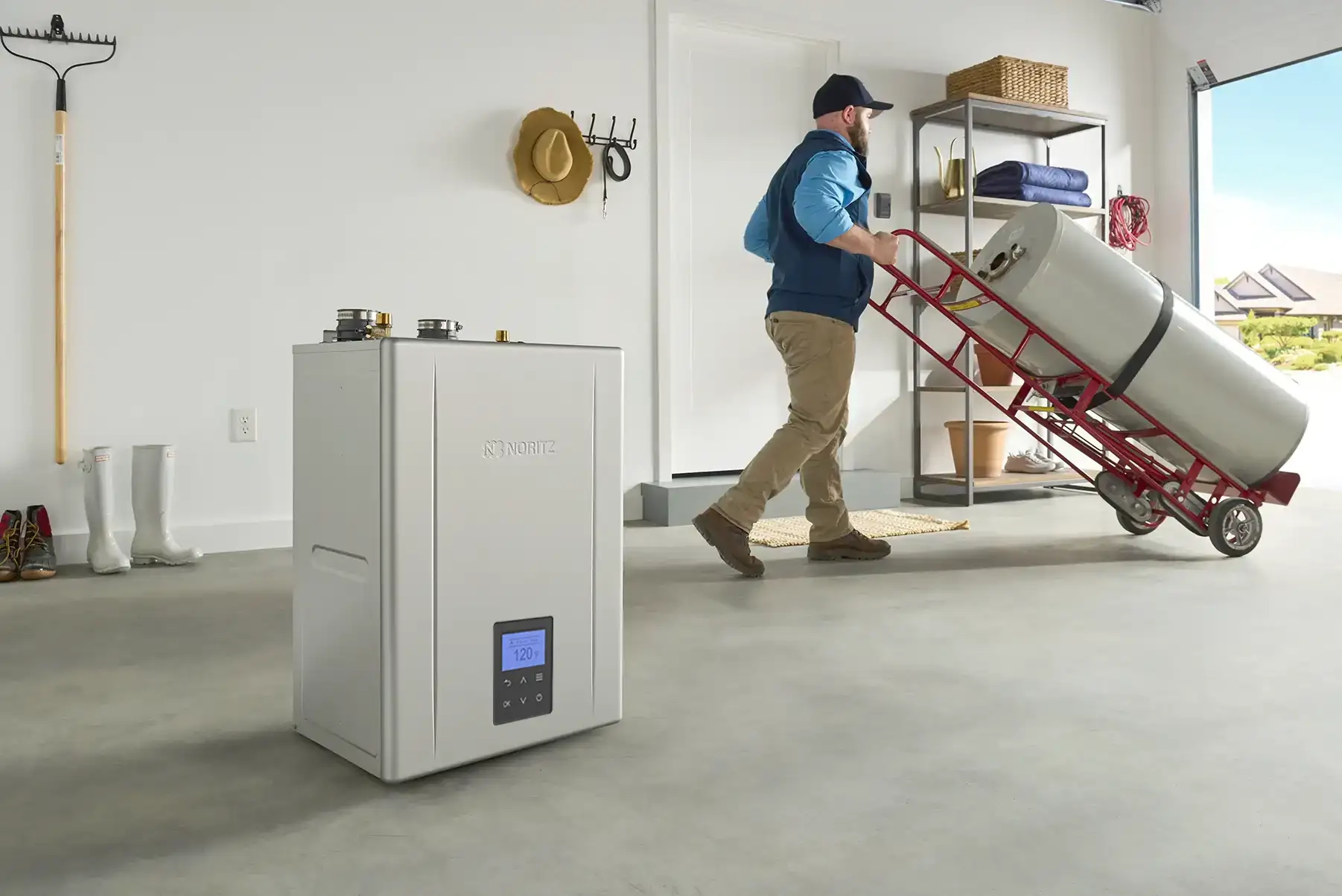 Installer moving a traditional tank water heater out while a tankless unit is ready